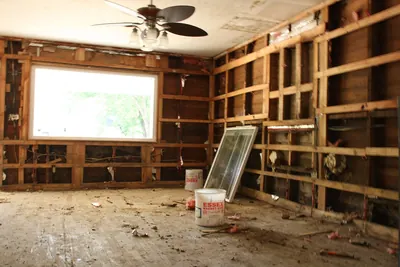 Room gutted to the studs with a large window and bare floor
